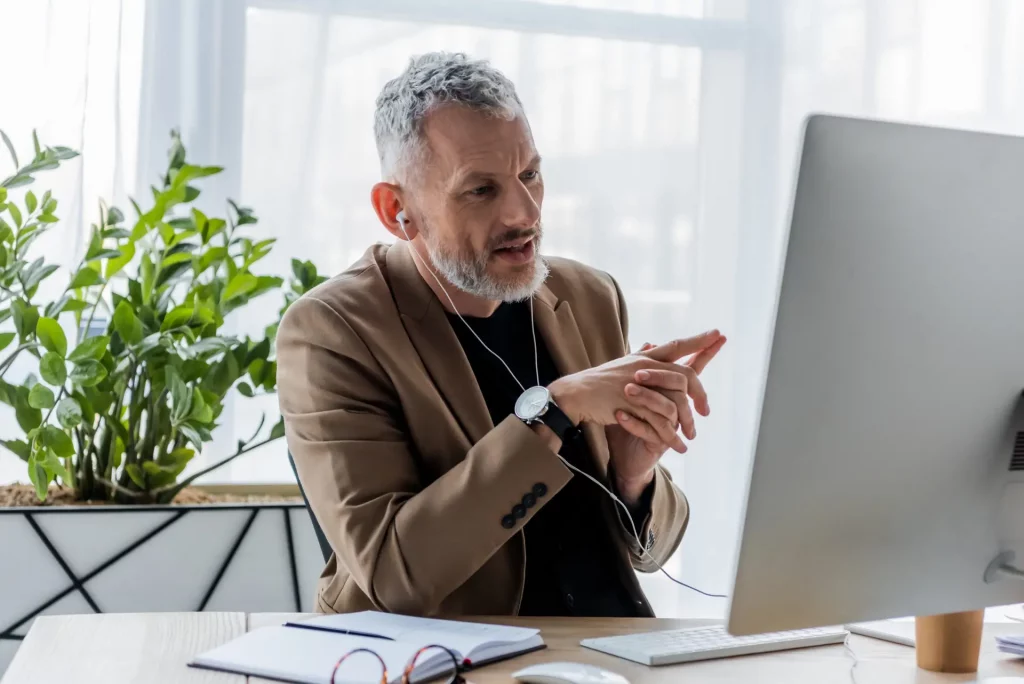 Executive coach at a desk looking at a monitor while on a video conference call.