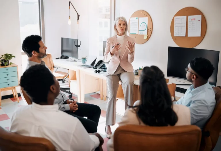 Woman presenting to a group of people in an office about why a coaching credential matters.