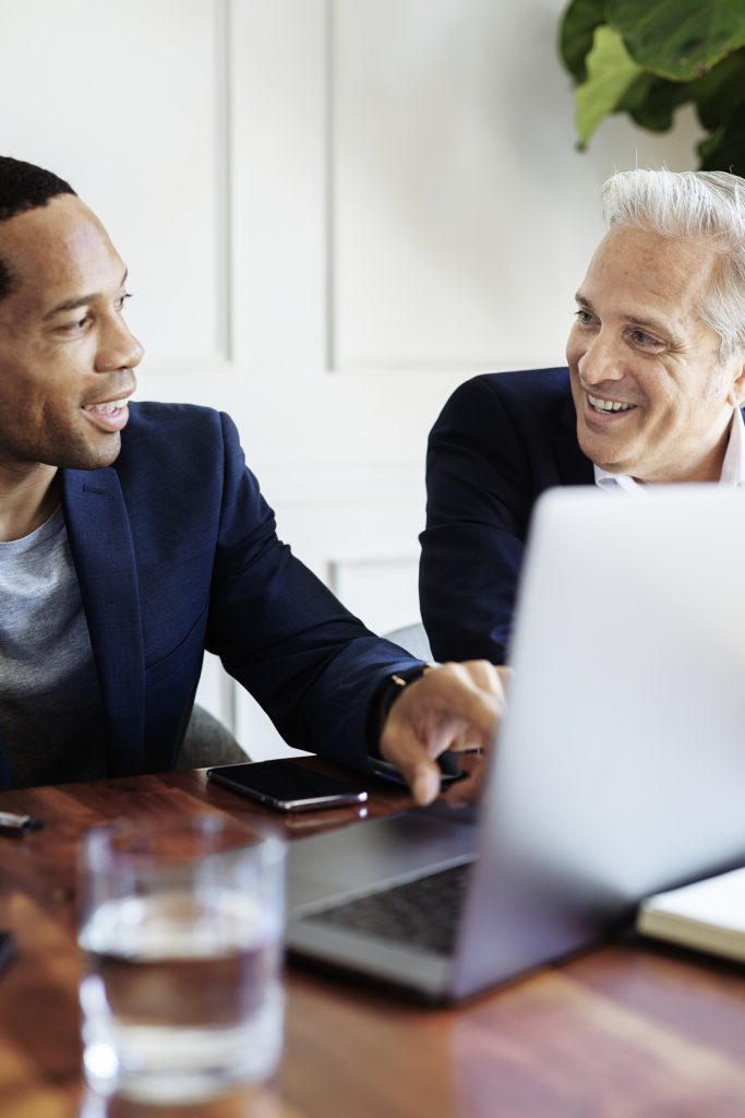 two businessmen sitting talking with computer