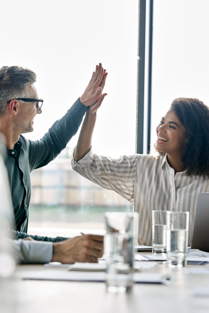 Two happy international business partners giving highfive at modern office.