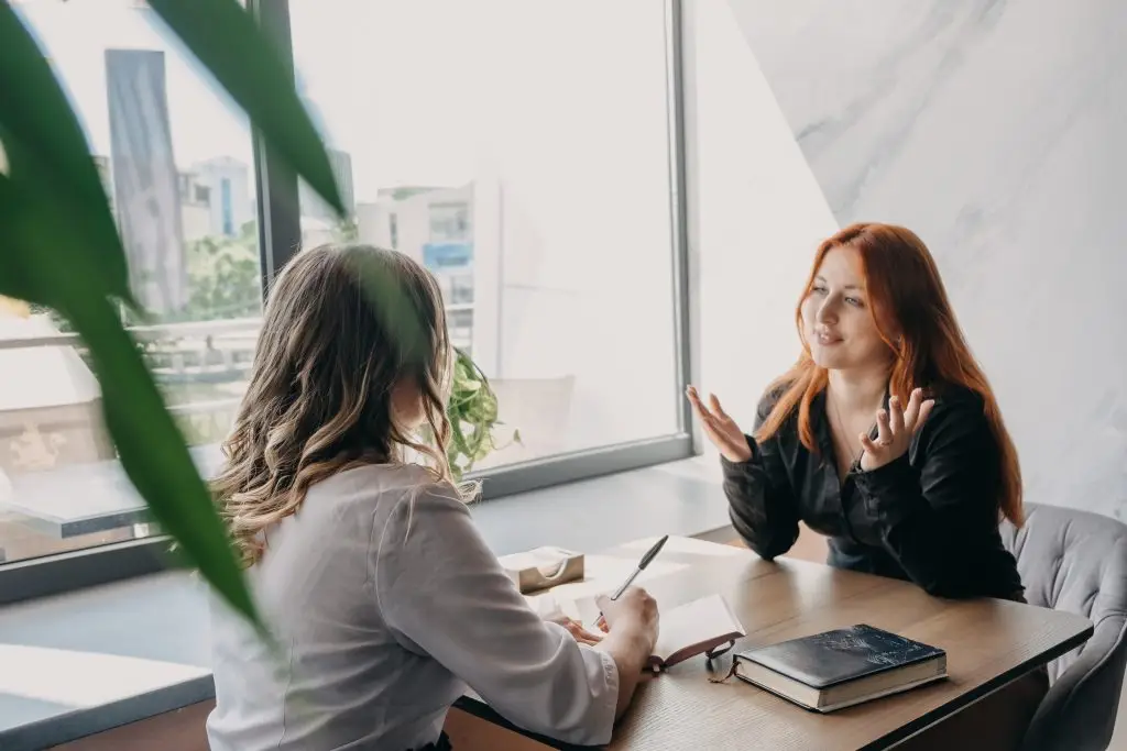 Two women are having a discussion in a bright, modern space.