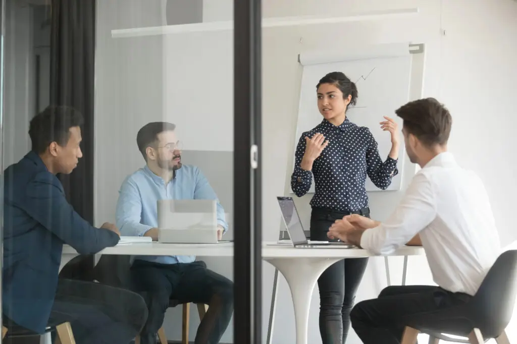 people meeting in closed door room with whiteboard for coaching