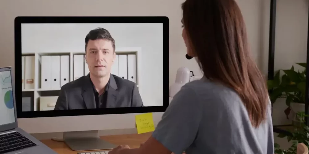 Businesswoman working alone behind table and having online meeting with coworker