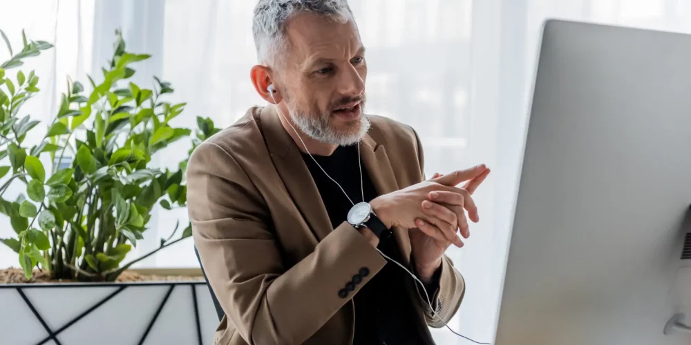 Executive coach at a desk looking at a monitor while on a video conference call.