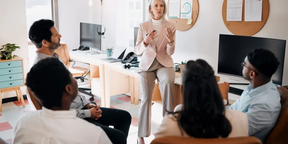 Woman presenting to a group of people in an office about why a coaching credential matters.